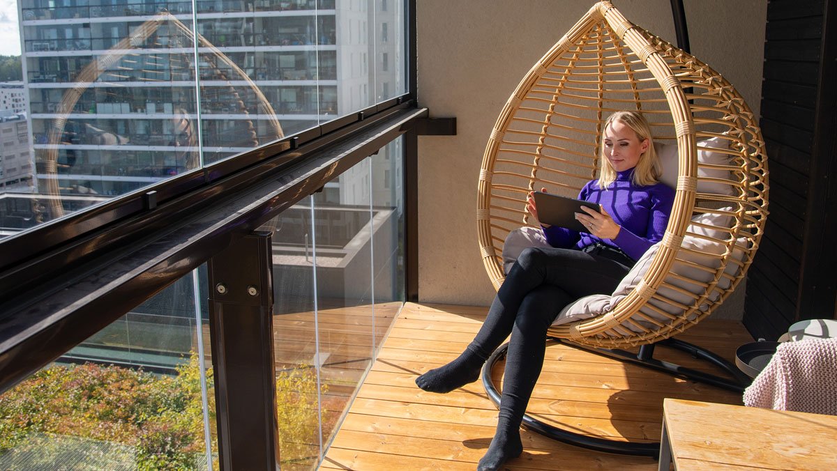 Nainen istuu riippukeinossa parvekkeella